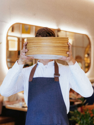 Waiter holding plates in front of his face, providing service at restaurant.