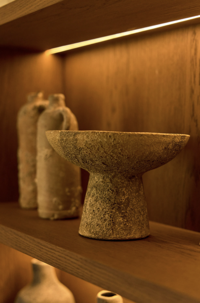 Decorative stone vase on shelf with bottles, wooden background details.