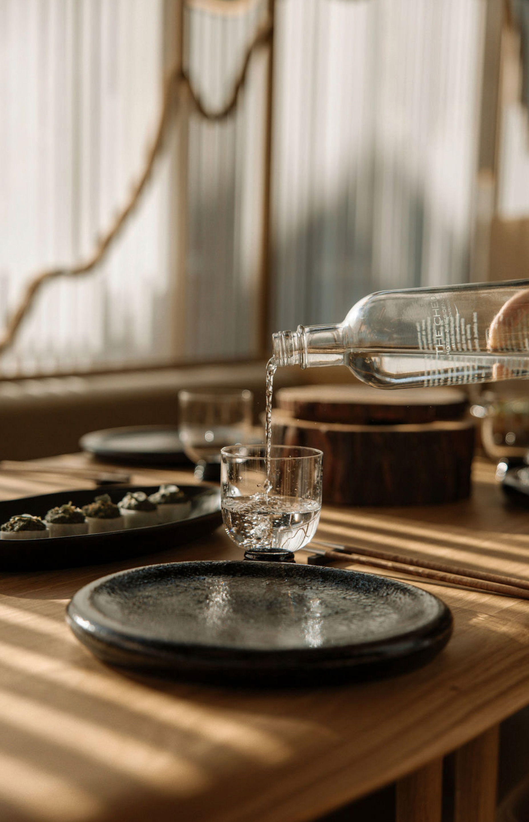 Pouring water into a glass at a table setting with plates and food.