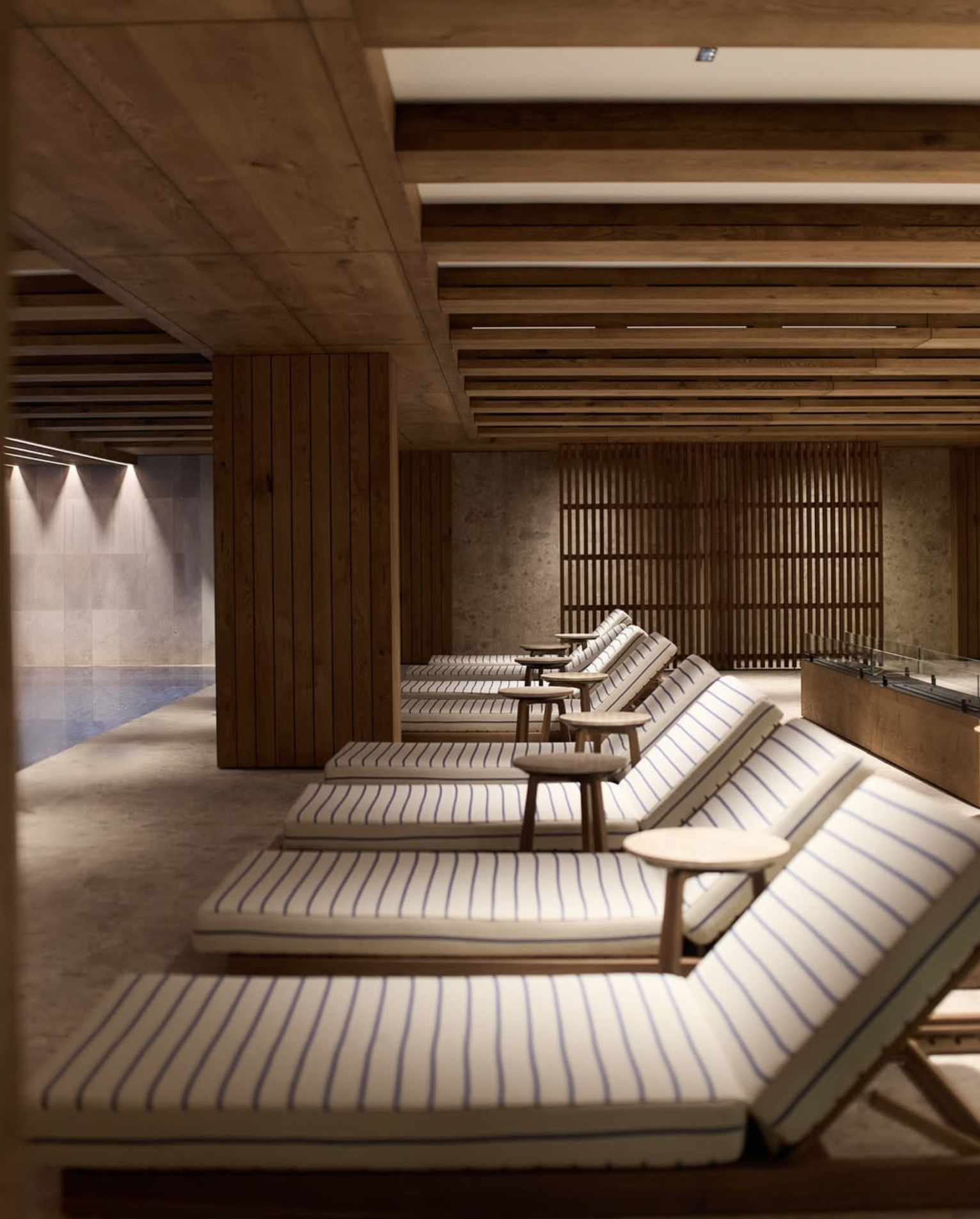 Spa lounge with striped chairs near a pool in a wooden room