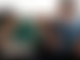 Two smiling songwriters co-writing together, one with a laptop and coffee, the other playing electric guitar, capturing the joy of collaboration.