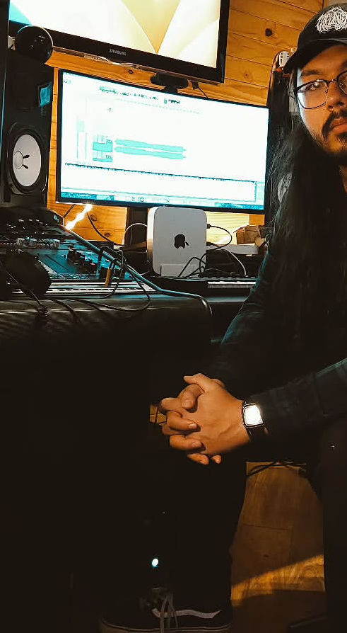 Luc sitting in a chair infant of his recording setup. 