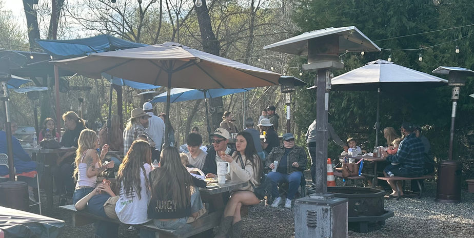 Friends and family dining outdoors during a monthly Saturday fish fry at Tollhouse Market and Grill