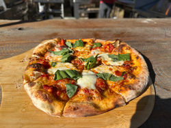 Wood-fired Margherita pizza topped with fresh mozzarella, basil, and tomato sauce