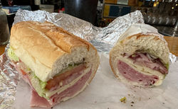 Ham, salami, and provolone cheese with mayo, lettuce, tomato, onion, dressing on a French roll