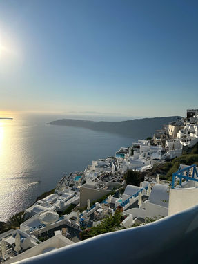 Panoramic view of the Santorini Caldera and white cliffside villages at sunset.