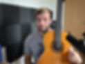 Picture of Jonny Albion pointing to a guitar in a home studio