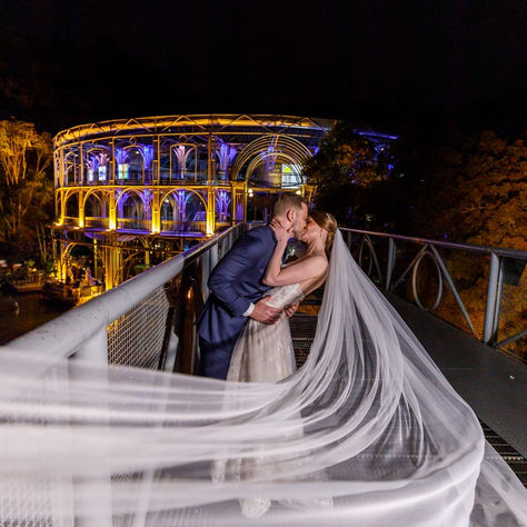 Barbara e Fabiano se beijam à noite com o véu longo esvoaçando, no dia do casamento