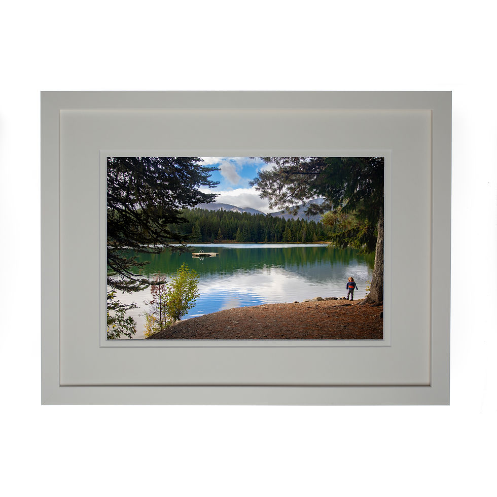A photo of the Lost Lake the trees frame the image as the sky and mountains reflect into the lake, with a white frame