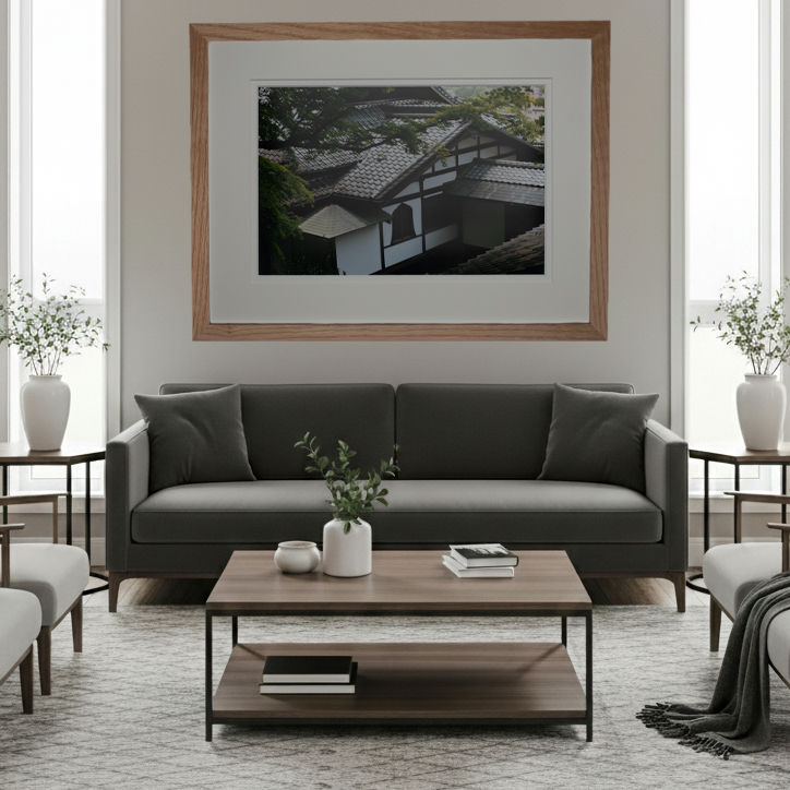 A wall art print of an old Japanese building viewed from the trees with an oak frame displayed in a living room