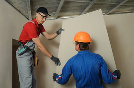 A picture of two workers installing drywall