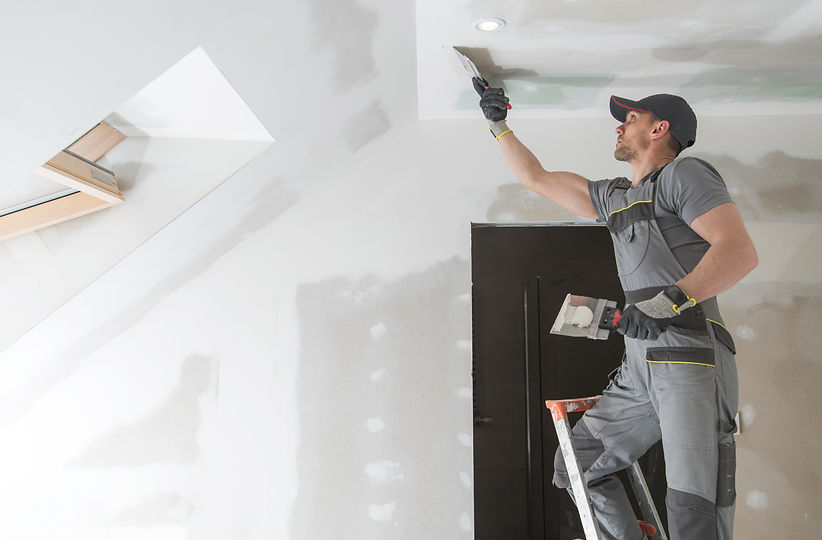 A photograph depicting a construction worker applying drywall tape