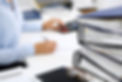 Foreground of stacked files with person working in the background