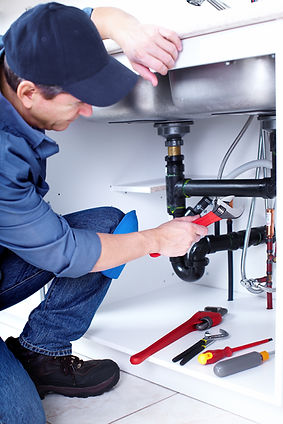 A plumber fixing the pipes under a sink