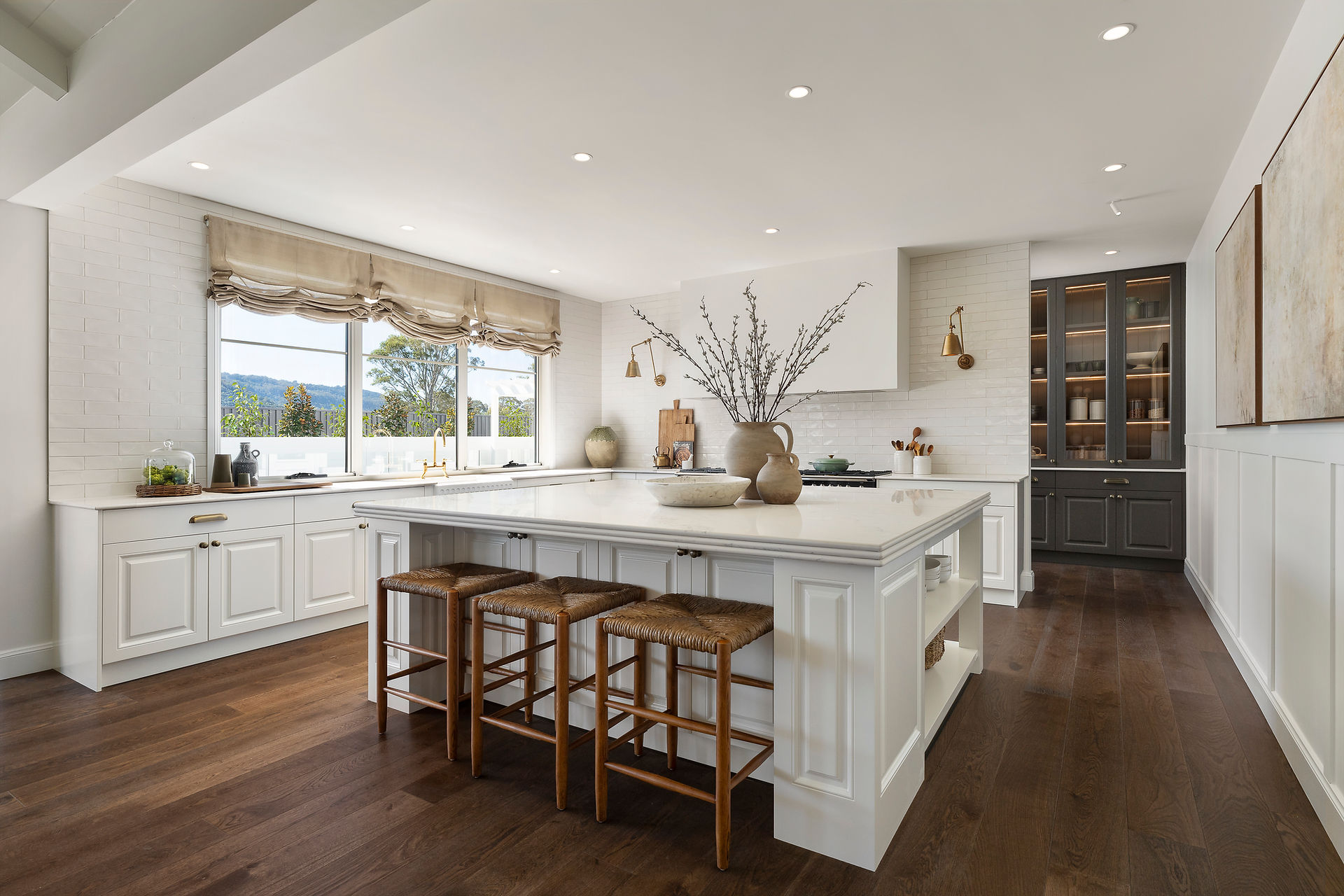 Modern farmhouse kitchen with oversized kitchen island bench. All white cabinetry with walnut toned timber look flooring.