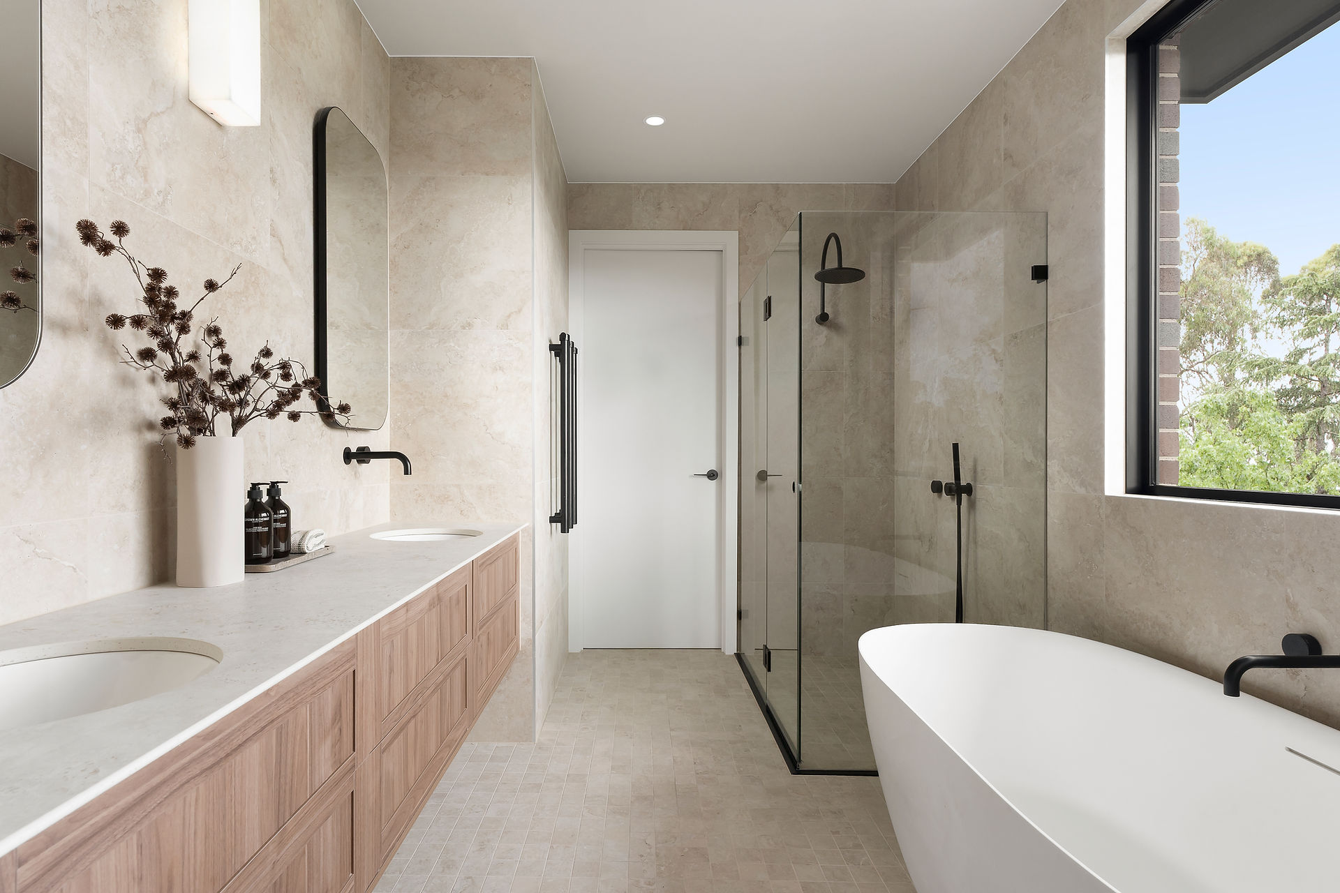 Ensuite bathroom with twin sink vanity, freestanding bath and large walk in shower with stone tiles and matte black tapware.
