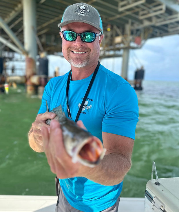 Captain Donnie holding fresh catch on Gulf Coast fishing trip with Team Vinson Charters