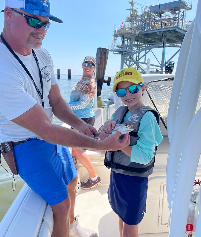 Captain Donnie and young angler holding a freshly caught fish on a family-friendly fishing charter with Team Vinson Charters