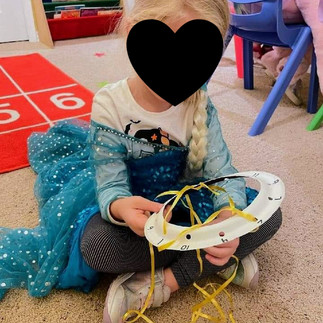 girl in elsa dress making a string spider web