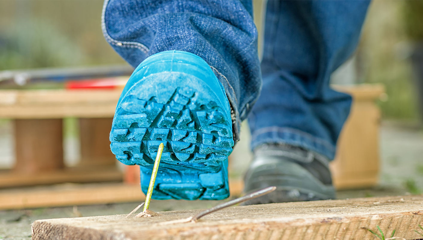 Nahaufnahme der Sohle eines Stiefels, der in Kürze von einem großen Nagel durchbohrt werden wird.