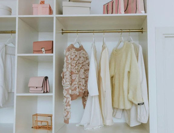 Organized bedroom closet with clothes and purses.
