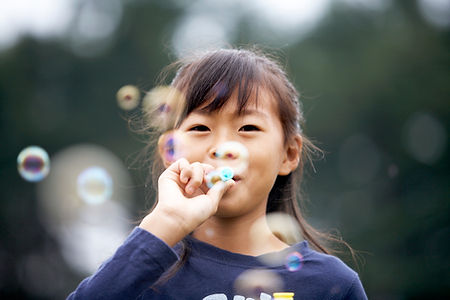 Child with a healthy airway blowing bubbles outside