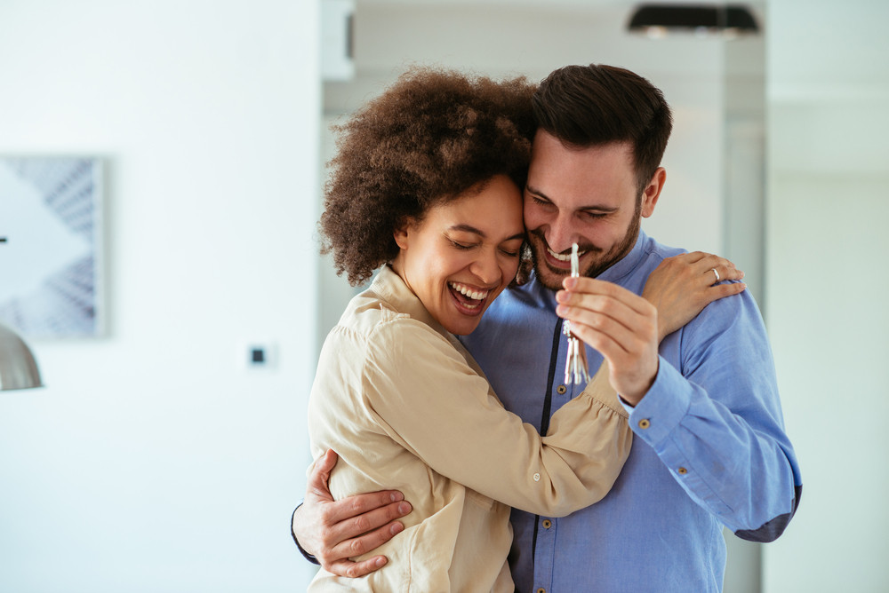 Couple hugging and holding house keys