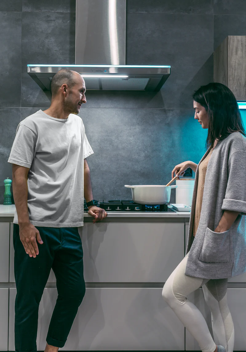 Couple standing in front of the kitchen stove, looking somber