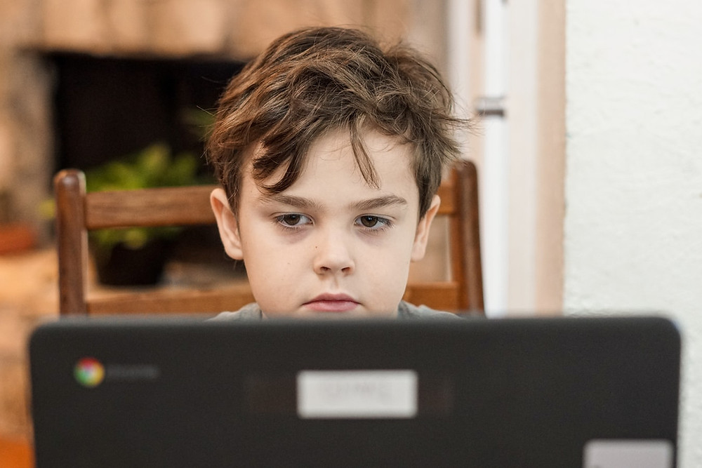Tired kid sitting behind laptop