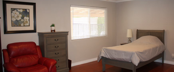 Comfortable bedroom with bed, red recliner, dresser. Ideal for 24 hour senior living.