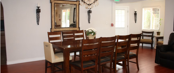 Elegant dining room with large table, chairs, chandelier, and mirror.