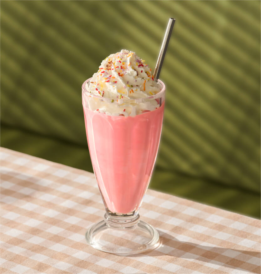 Herramienta de mejora de imagen aplicada a una foto de un batido rosa, que mejora la nitidez, la iluminación y el contraste, manteniendo la composición original.