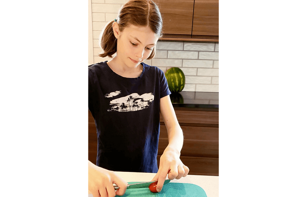 Jeune fille coupant une tomate cerise avec la technique du tunnel