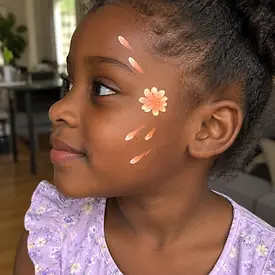 Girl with orange face painted flowers