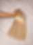 Hand holding silky blonde hair extensions bundles