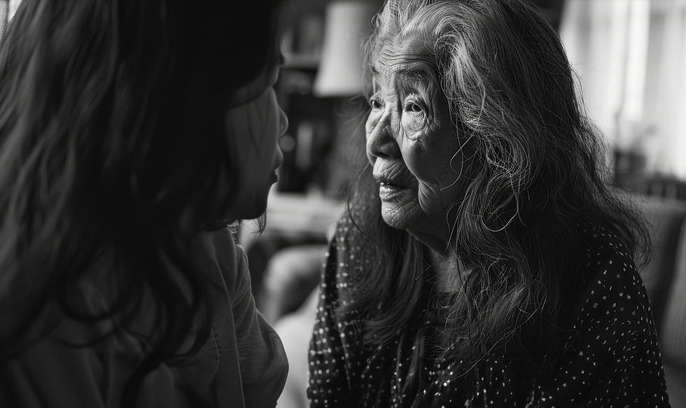 Elderly woman with long hair gazes at a child in a cozy room. B&W image captures warmth and connection in tender moment.