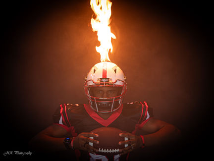 Football player with flames on helmet holding ball, Sports Portrait, Joyful Aperture Juanita's Photography