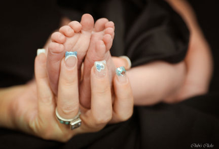 A hand holding tiny baby feet, New Born, with black background, Joyful Aperture Juanita's Photography