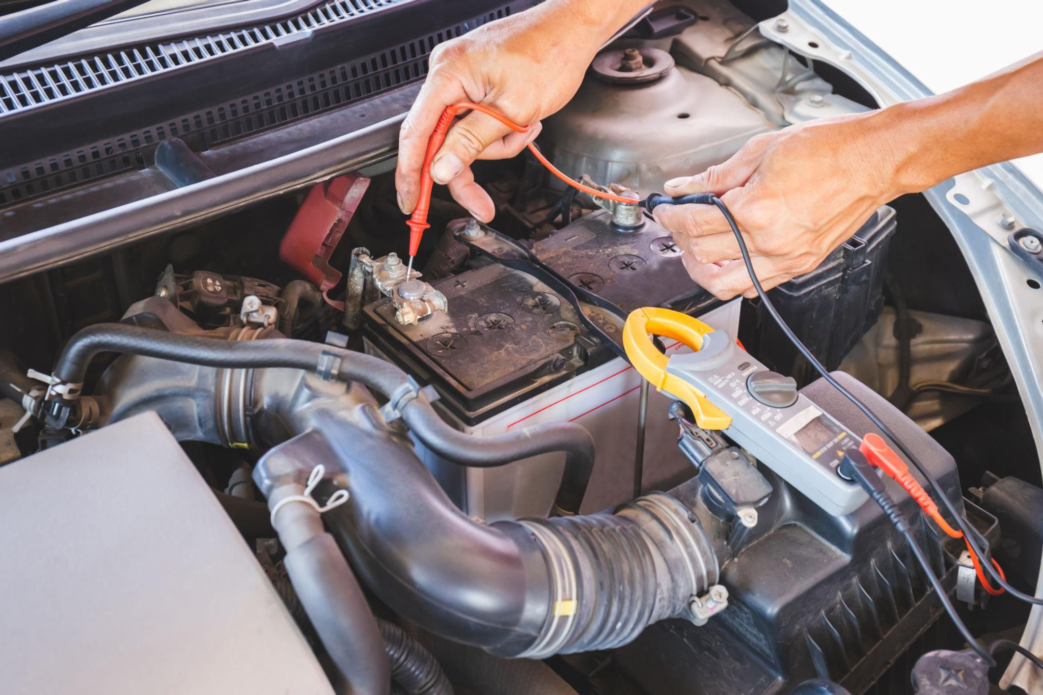 Hands testing car battery, electrical repairs