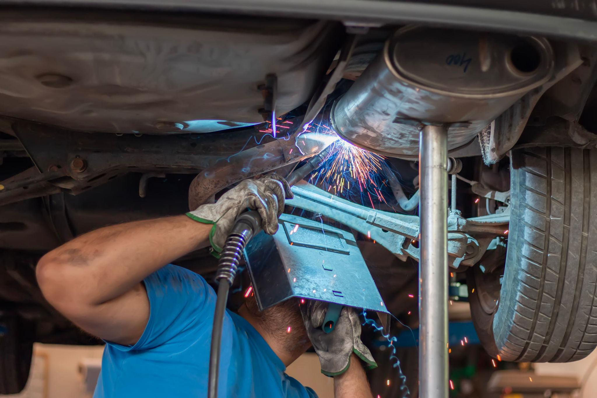 Mechanic welding a car exhaust system