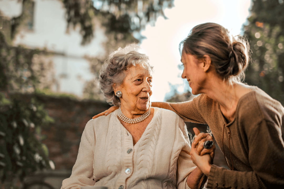 Eine Frau ist sehr präsent und hört einer Seniorin aufmerksam beim Gespräch zu