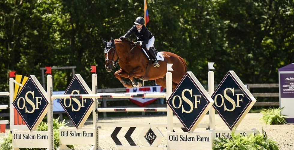 Head trainer of Hart Farms, Emma Callanan jumping with her horse over a large oxer at The Old Salem Horse Show in the jumpers.