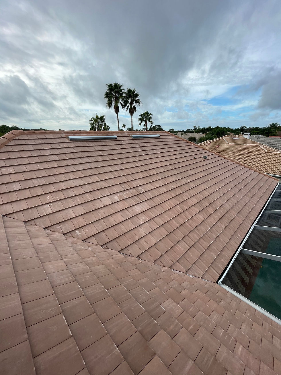 Concrete tile roof with two roof vents on a Florida home under a cloudy sky.