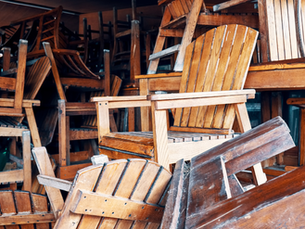 Wooden chairs and furniture piled up in a messy space waiting to be hauled away