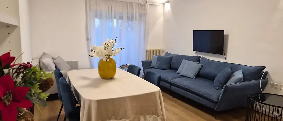 Bright living room with blue sofa and dining table, light wood flooring rechavia jerusalem