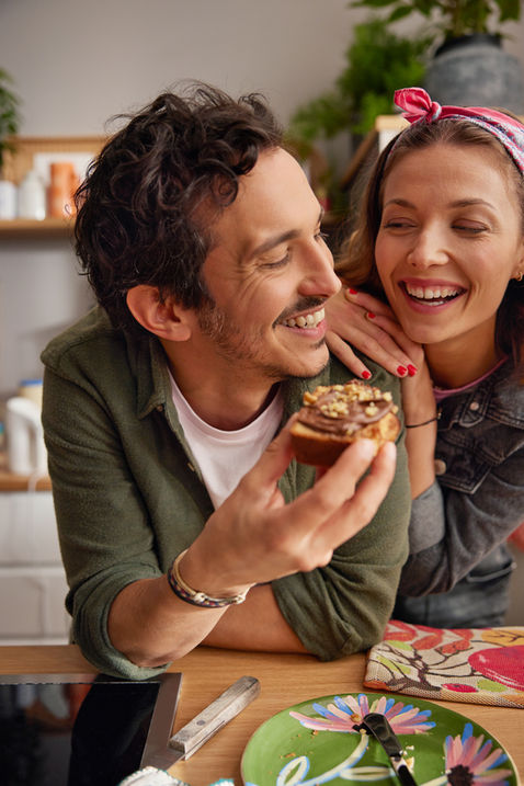 Paar lacht, Mann hält ein belegtes Brot – Lifestylefotografie von Andreas Reimann