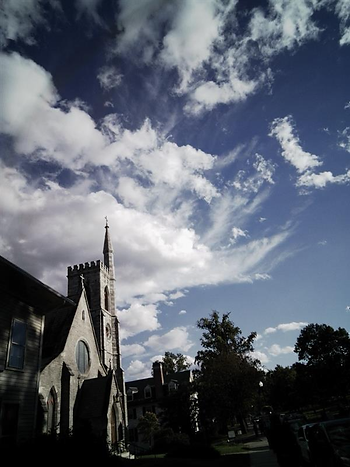 A beautiful, older church in downtown Amherst, Massachusetts is shown against a blue and cloudy sky.