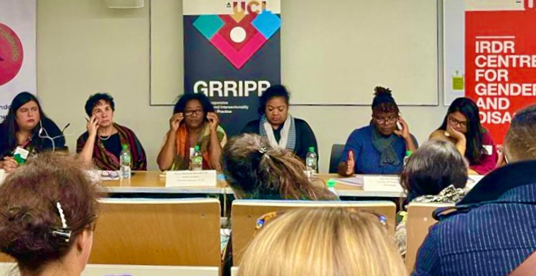 Seis mujeres se sientan erguidas en un panel detrás de placas oficiales con sus nombres y organizaciones. Detrás de ellas, una pancarta con el logotipo del GRRIPP en vivos colores. Las mujeres parecen a la vez pensativas y decididas: algunas miran al exterior pensativas, otras miran al público detrás del objetivo, algunas toman notas.