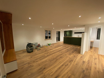 Bei diesem Projekt war eine umfassende Kernsanierung mit zahlreichen Renovierungsarbeiten, darunter sämtliche Elektroinstallationen, teilweise neue Fenster und Türen, neue Küche und Badezimmer, eine neue Heizung sowie neue sanitäre Installationen. Die Bauherrschaft hatte klare Vorstellungen und Wünsche, wie ihr perfektes Haus aussehen sollte und die Aufgabe bestand darin, diese Wünsche in die Tat umzusetzen, ohne das Budget zu sprengen.
Dank intensiver Gespräche und Planungen konnte schließlich eine detaillierte Kostenschätzung erstellt werden, die den Anforderungen der Bauherrschaft entsprach. Die Innenarchitektur und das Raumkonzept wurden mithilfe modernster Hilfsmittel in 3D geplant, um ein modernes und gemütliches Ambiente zu schaffen.
Insgesamt wurde bis auf die Aussenmauern alle Innenwände entfernt und einen neue Raumstruktur geschaffen. Damit die Bauherrschaft künftig keine lästigen Dübellöcher mehr bohren muss, ist in allen Wänden Holz verbaut, sodass nur eine Schraube benötigt wird, um etwas aufzuhängen.
Ein besonderer Fokus lag auf der Küche, und ist nun auch ein Zentrum des Hauses. Die grün lackiert Küche in U-Form mit grosser Inselfläche und integrierter Bar, ist ein echtes Highlight. Durch das Borakochfeld mit integriertem Dampfabzug, kann auf ein störender Abzug verzichtet werden. Praktische Stauraummöbel auf der Wohnzimmerseite bieten genügend Platz für Accessoires, Spezialgeschirr oder Spielsachen.
Auch die beiden Badezimmer wurden komplett saniert und erstrahlen nun in neuem Glanz. Das neue Familienbad wurde mit einer Dusche, Badewanne und einem Doppelwaschbecken ausgestattet. Neben dem praktischen ins furnierter Eiche Möbel auf Mass in der Wand und den Badmöbel ist für ausreichend Stauraum gesorgt. Die praktischen in die Wand gebauten Ablagefächer in der Dusche und bei der Badewanne sind nicht nur optisch ein Hingucker.
Das Gästebad im EG lädt Gäste ein, in Ruhe zu verweilen. Die Bodenebene Dusche ermöglicht Komfort auf höchstem Niveau.
Das massgefertige Möbel mit umlaufenden massivholzrahmen in Eiche rustikal im Wohnzimmer lädt zum lesen, verweilen oder träumen ein. Der Blick nach Aussen ist einfach unbezahlbar und gibt dem gesamten Raum eine wunderbare Harmonie zwischen Modern, Erdig und Wohnlichkeit.
Durch die enge Zusammenarbeit mit der Bauherrschaft, welche selbst viel Hand angelegt hat und die Verwendung moderner digitaler Lösungen konnten alle Arbeiten gemäss den Vorstellungen realisiert werden. Pünktlich zu Weihnachten waren die Arbeiten abgeschlossen und die neuen Räumlichkeiten wurden bezogen.
Wir sind stolz darauf, Teil dieses Projekts gewesen zu sein und bedanken uns herzlich für die tolle Zusammenarbeit. Das Ergebnis spricht für sich und zeigt, wie erfolgreich Teamarbeit sein kann, um die individuellen Wünsche der Bauherrschaft umzusetzen.
Weitere Bilder folgen in Kürze.