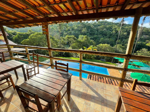 área para refeições e trabalhar com bela vista para floresta e piscina da pousada recanto do chalé